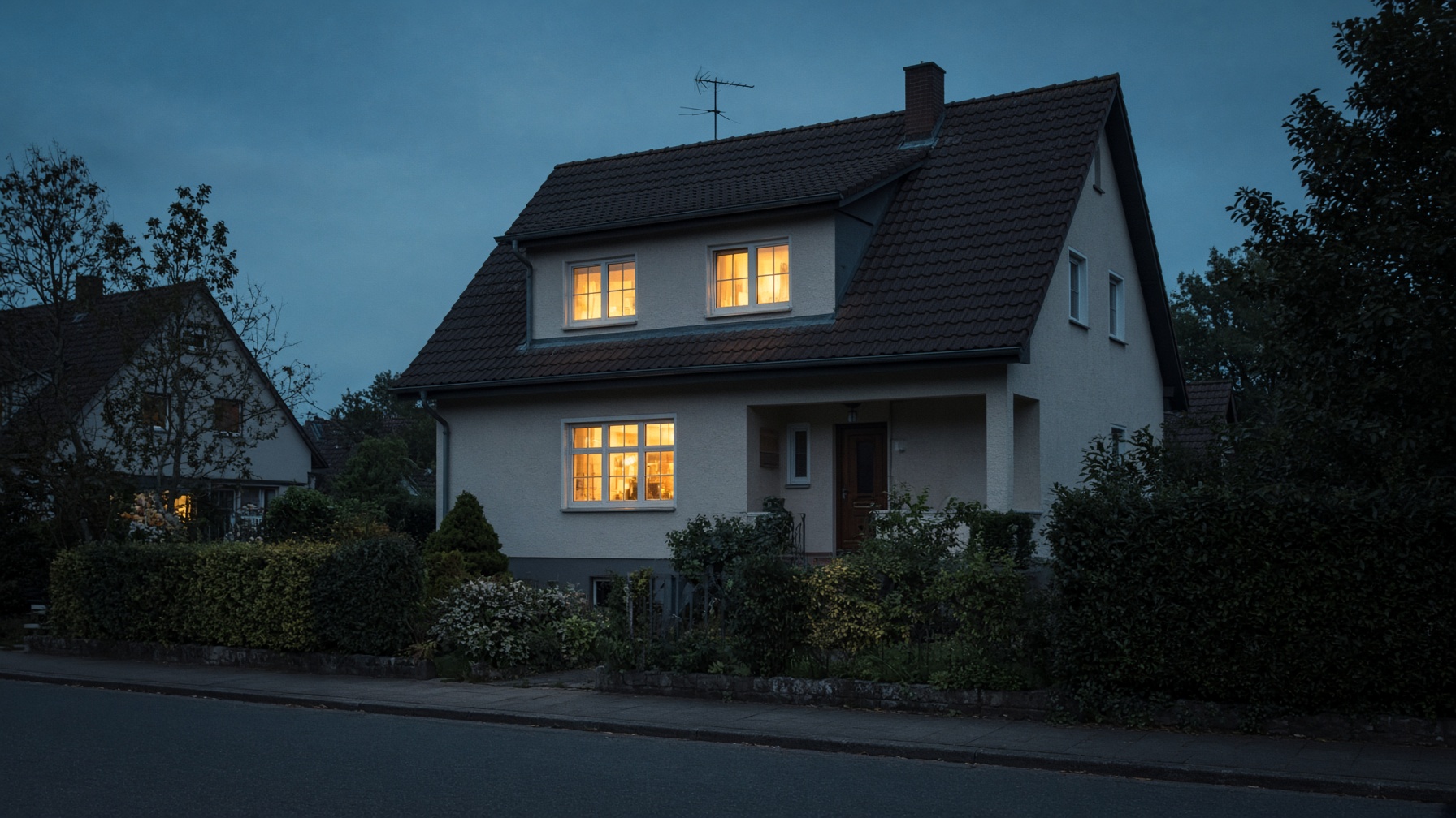 Wohnhaus in der blauen Stunde, warmes Licht in den Fenstern